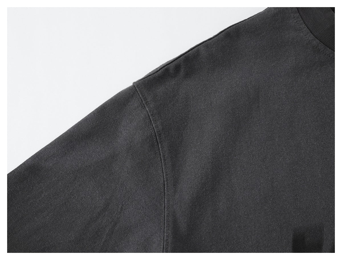 Close-up of a charcoal-black garment shoulder seam and ribbed neckline.