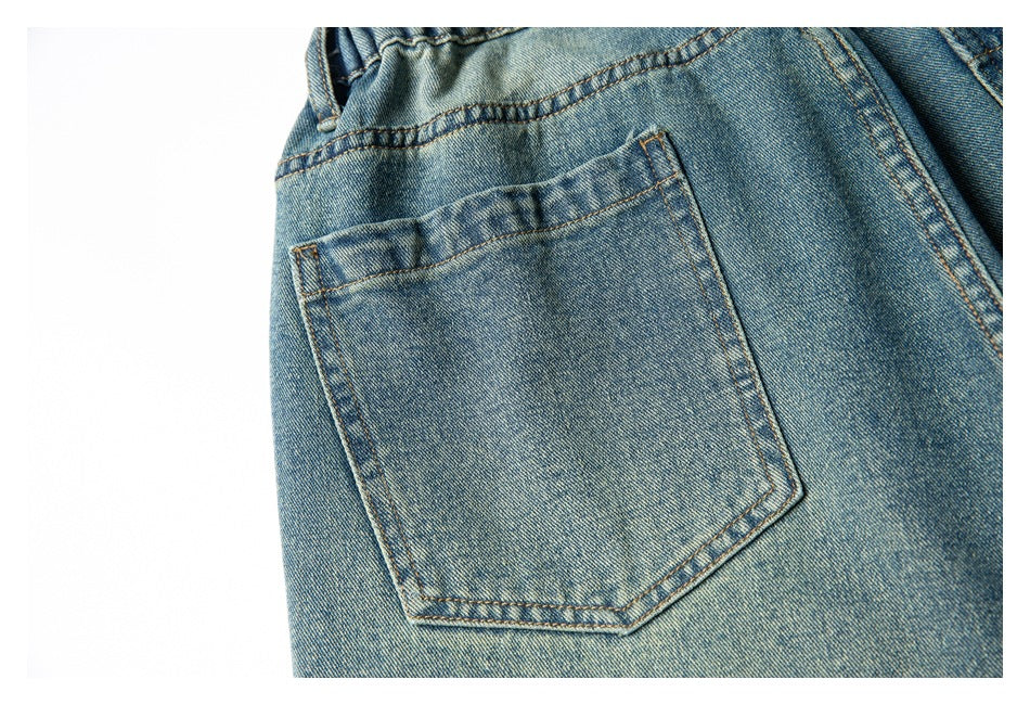 Close-up of a single rear patch pocket and stitched waistband on faded blue denim shorts.
