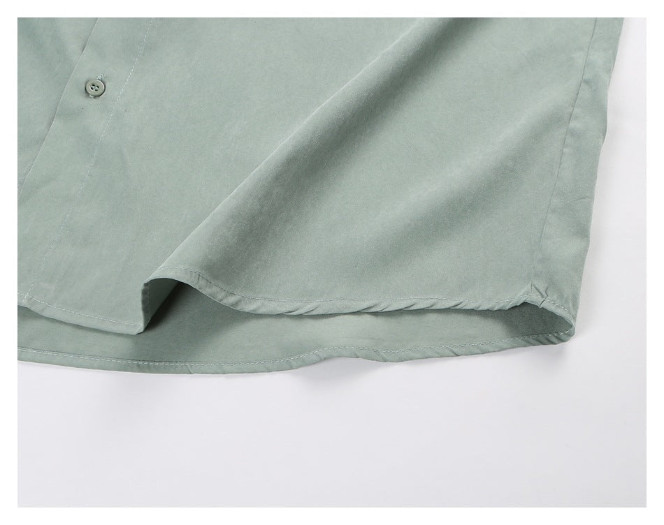 Close-up of the sage-green shirt's curved bottom hem and stitching.