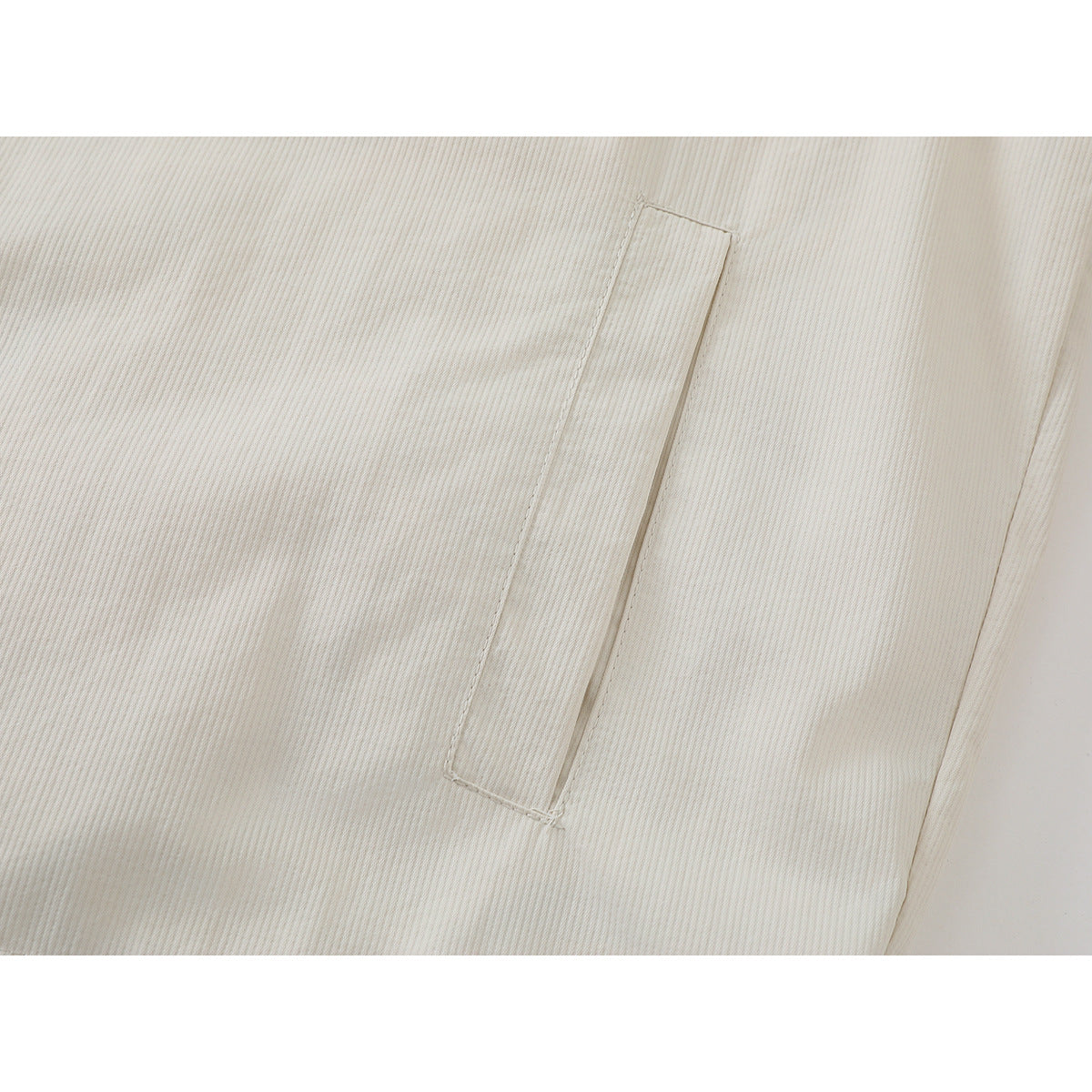 Close-up of the ivory ribbed shirt jacket's narrow vertical chest pocket and stitching.