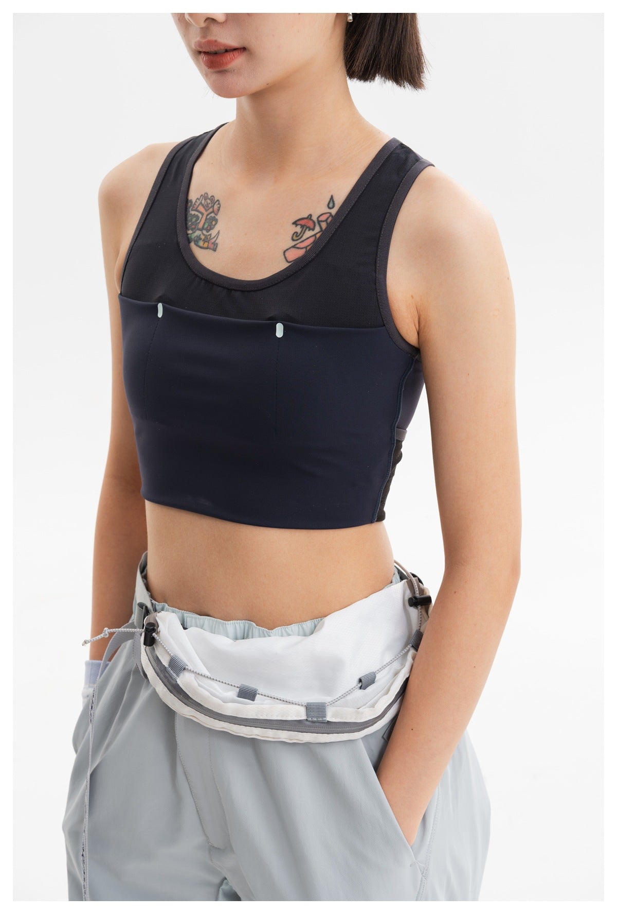 Close-up of a navy cropped tank with a black mesh upper panel and pale blue-gray pants waistband.