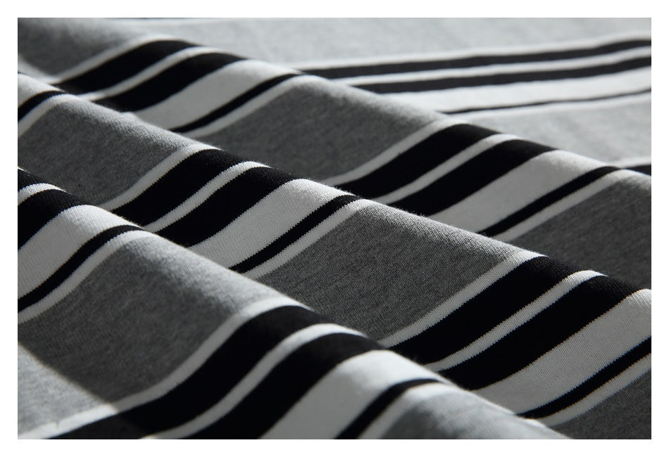 Close-up of gray knit fabric with alternating black and white horizontal stripes, draped in folds.