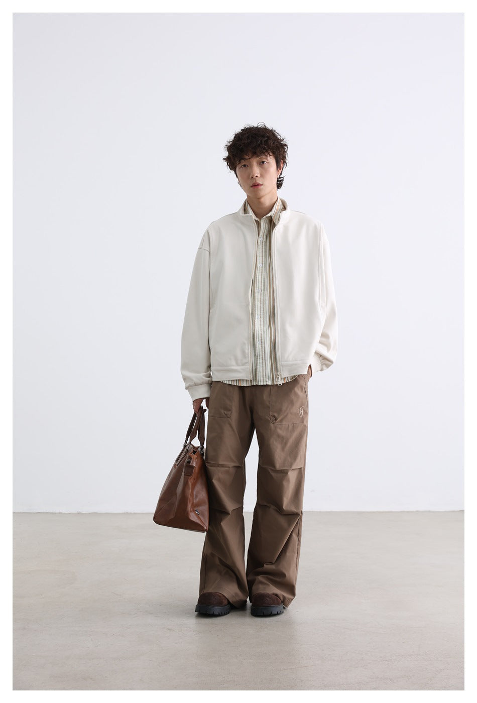 Front view of a model in an off-white zip jacket over a striped shirt and brown cargo pants.
