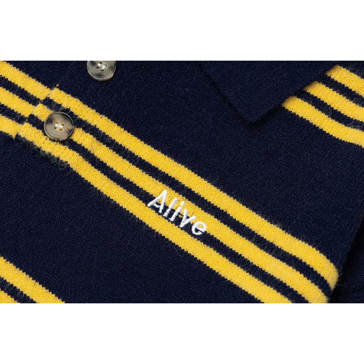 Close-up of yellow stripes and white embroidered lettering on a navy knit sweater, with two buttons visible.