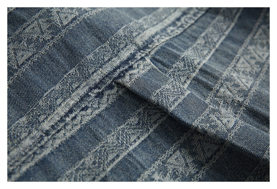 Close-up of folded blue patterned denim fabric with visible seams and decorative bands.