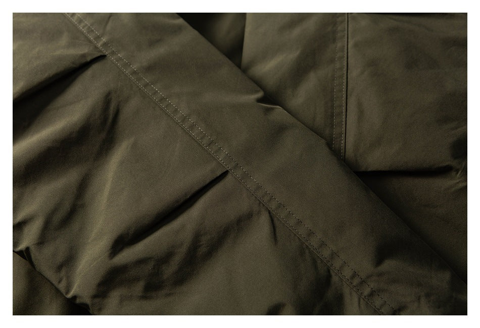 Close-up of an olive garment with a diagonal double-stitched seam.
