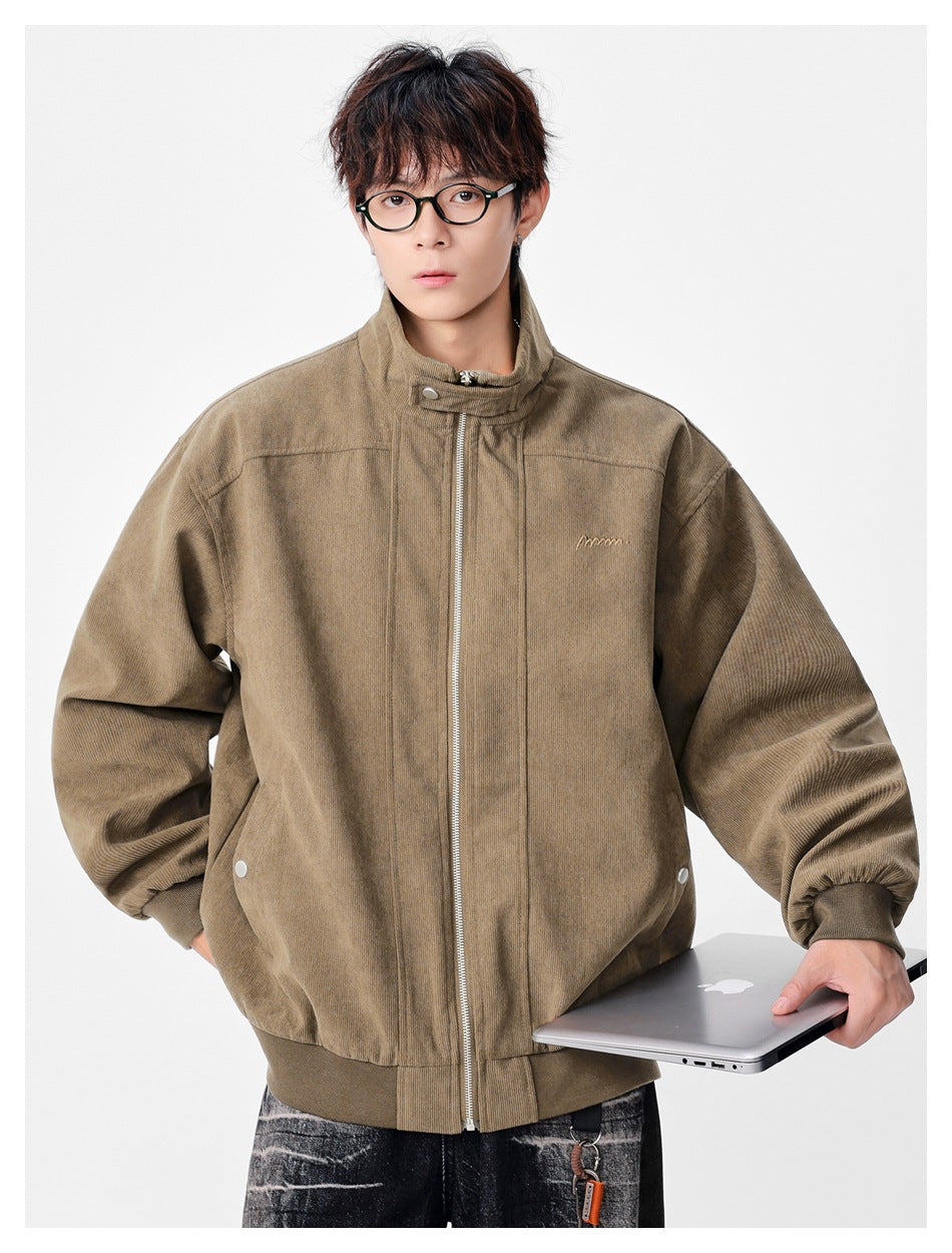 Model wearing khaki ribbed stand-collar zip jacket, holding a laptop, front view