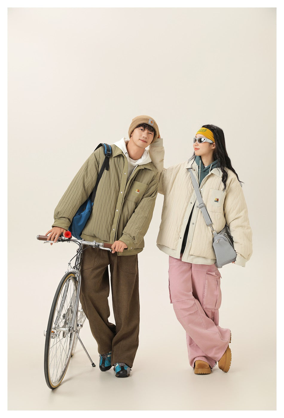 Two models pose with a bicycle, wearing olive and cream quilted button-front jackets with chest pockets.