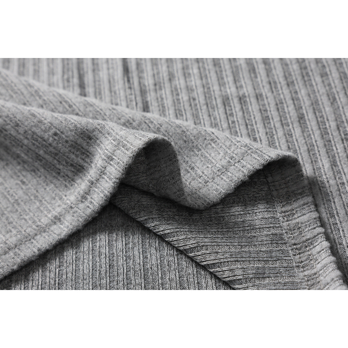Close-up of heather gray ribbed fabric folded to show its texture and inner stitching.