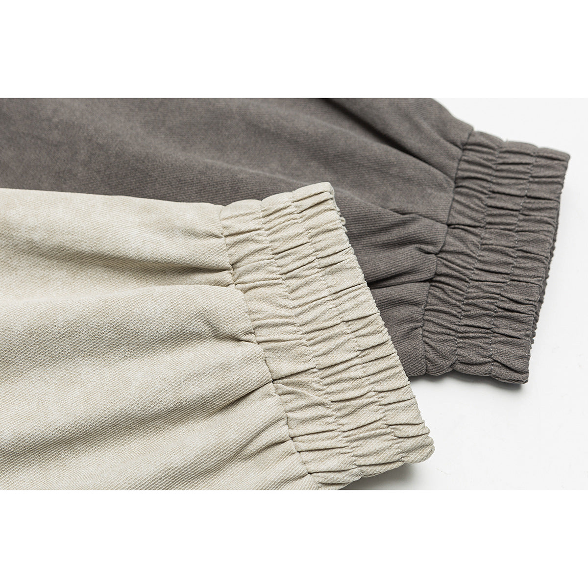 Close-up of gathered elastic cuffs on light beige and charcoal gray jacket sleeves.