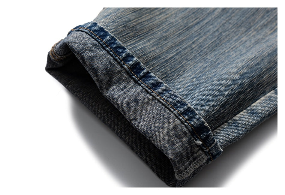 Close-up of a cuff turned up on faded blue jeans, showing the hem stitching and inner denim.