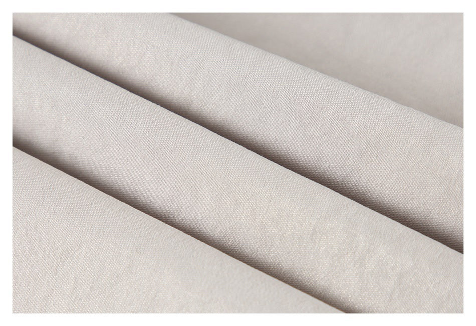 Close-up of pale beige garment fabric folded to show its fine woven texture.
