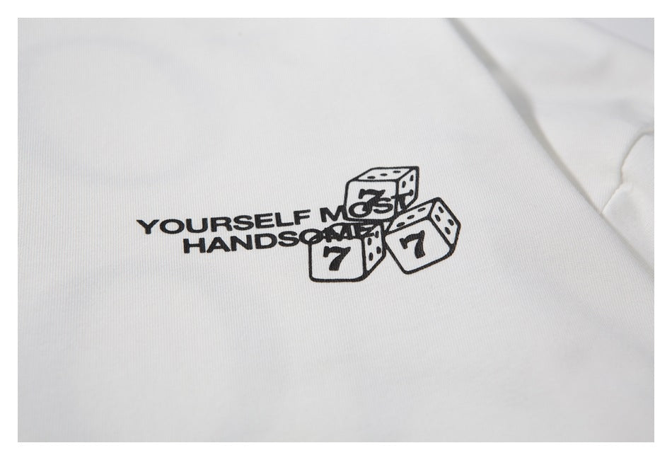 Close-up of black dice artwork and English lettering printed on a white T-shirt.