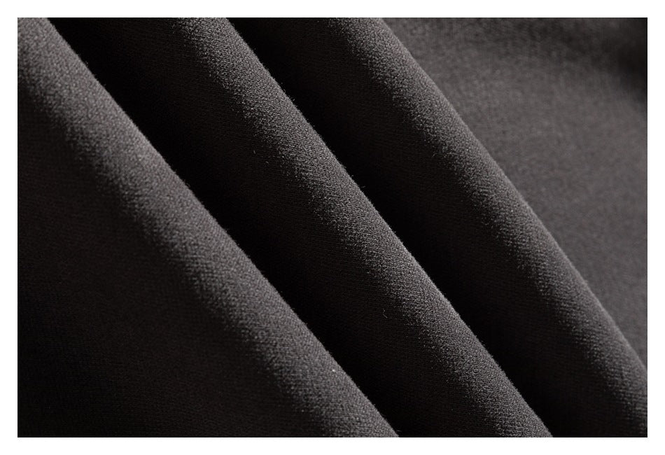 Extreme close-up of dark sweatshirt fabric arranged in soft folds, showing its surface texture.