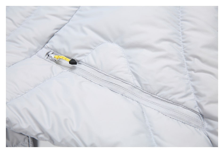 Close-up of a diagonal zipper pocket on a light gray quilted jacket with a yellow cord pull.