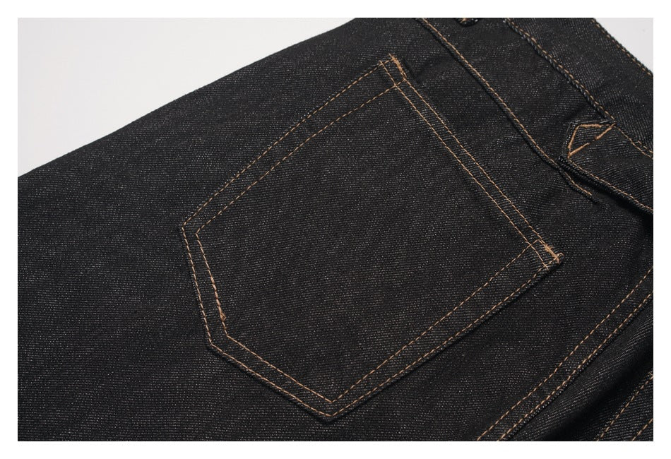 Close-up of a rear patch pocket on black denim trousers, outlined with tan stitching.
