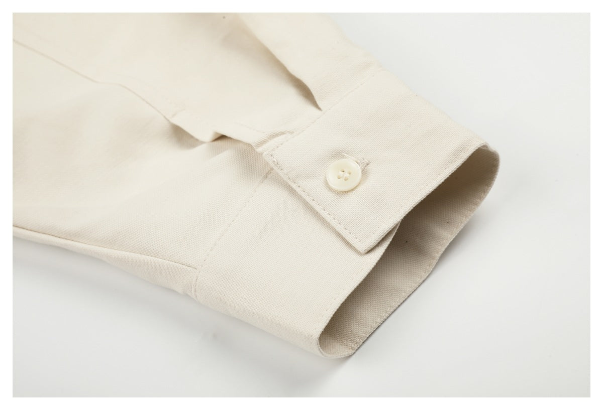 Close-up of an ivory cuff with a cream button, stitched seams, and folded edge.