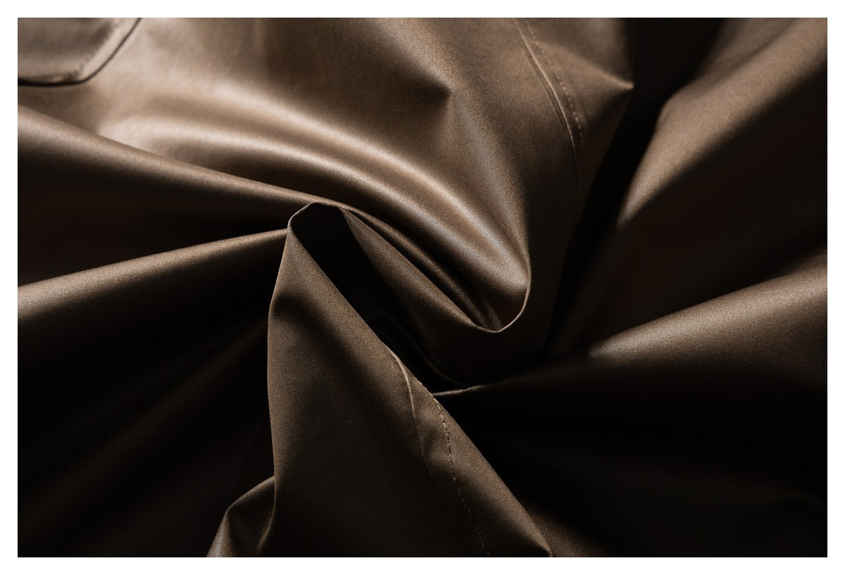 Close-up of smooth, glossy dark brown jacket fabric folded to show its sheen and drape.