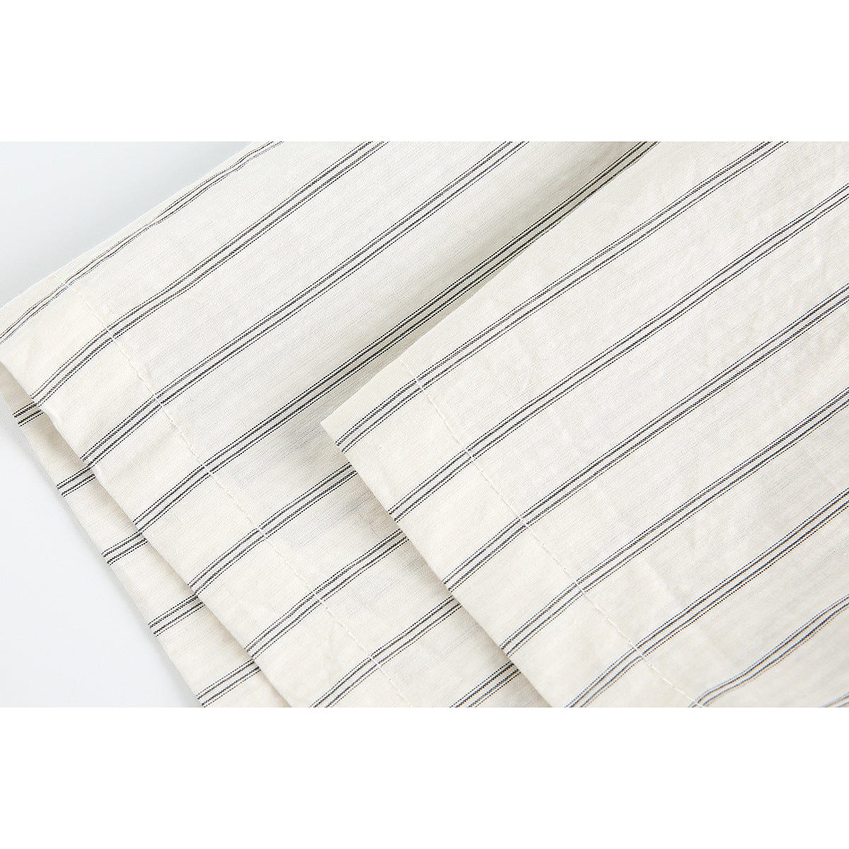 Close-up of the striped off-white shirt fabric and a folded, stitched edge.