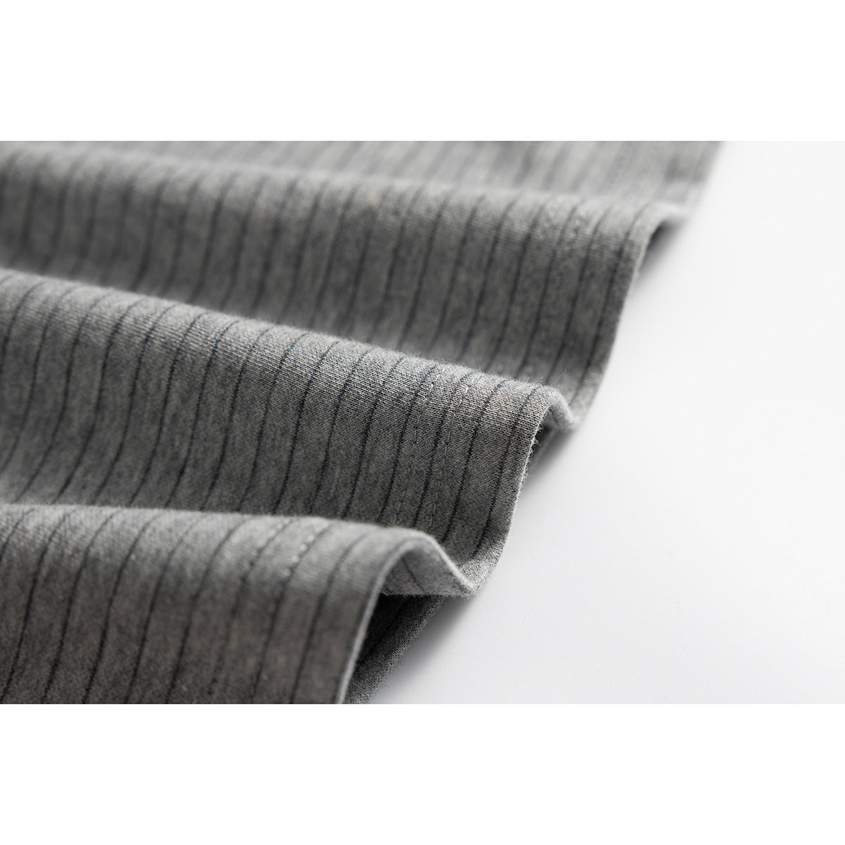 Close-up of gray shirt fabric folded into soft ridges, showing its fine dark stripe pattern.