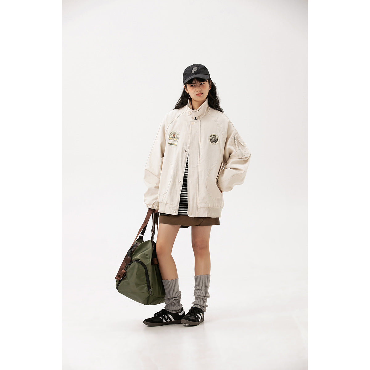 A model wears a cream oversized jacket with chest patches, snap front, large pockets and elastic cuffs.