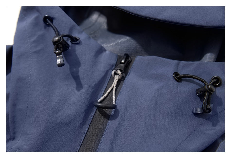 Close-up of a slate-blue jacket hood showing black drawcord toggles and a central zipper pull.