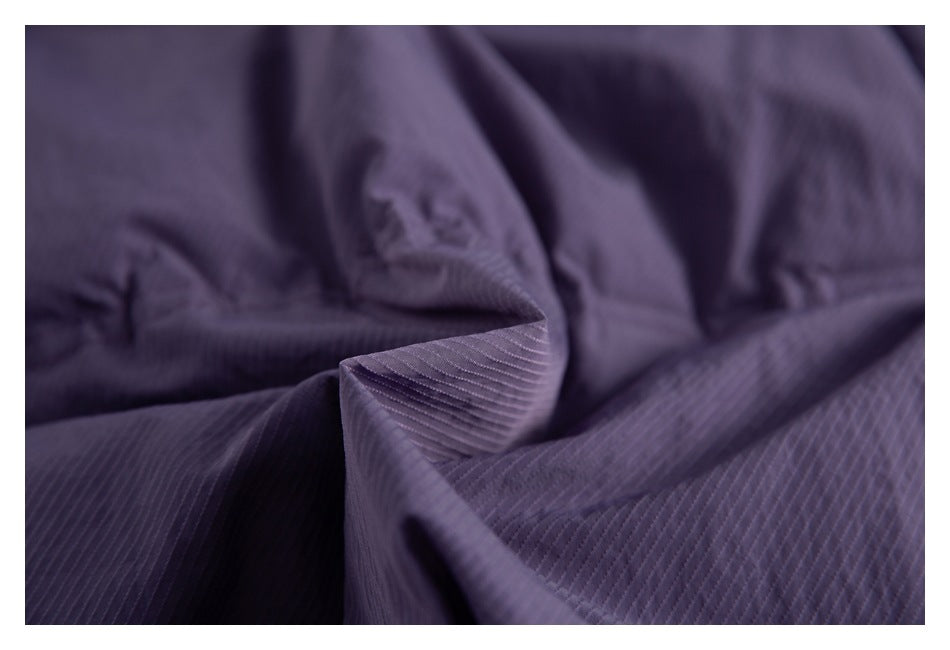 Macro view of dark purple fabric showing its fine ribbed texture and stitching.