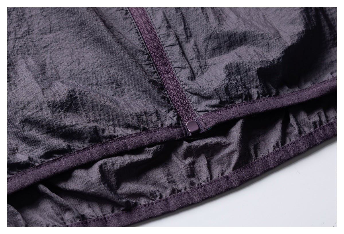 Close-up of a dark purple-gray garment showing a zipper, stitched panel seams, and a curved hem.