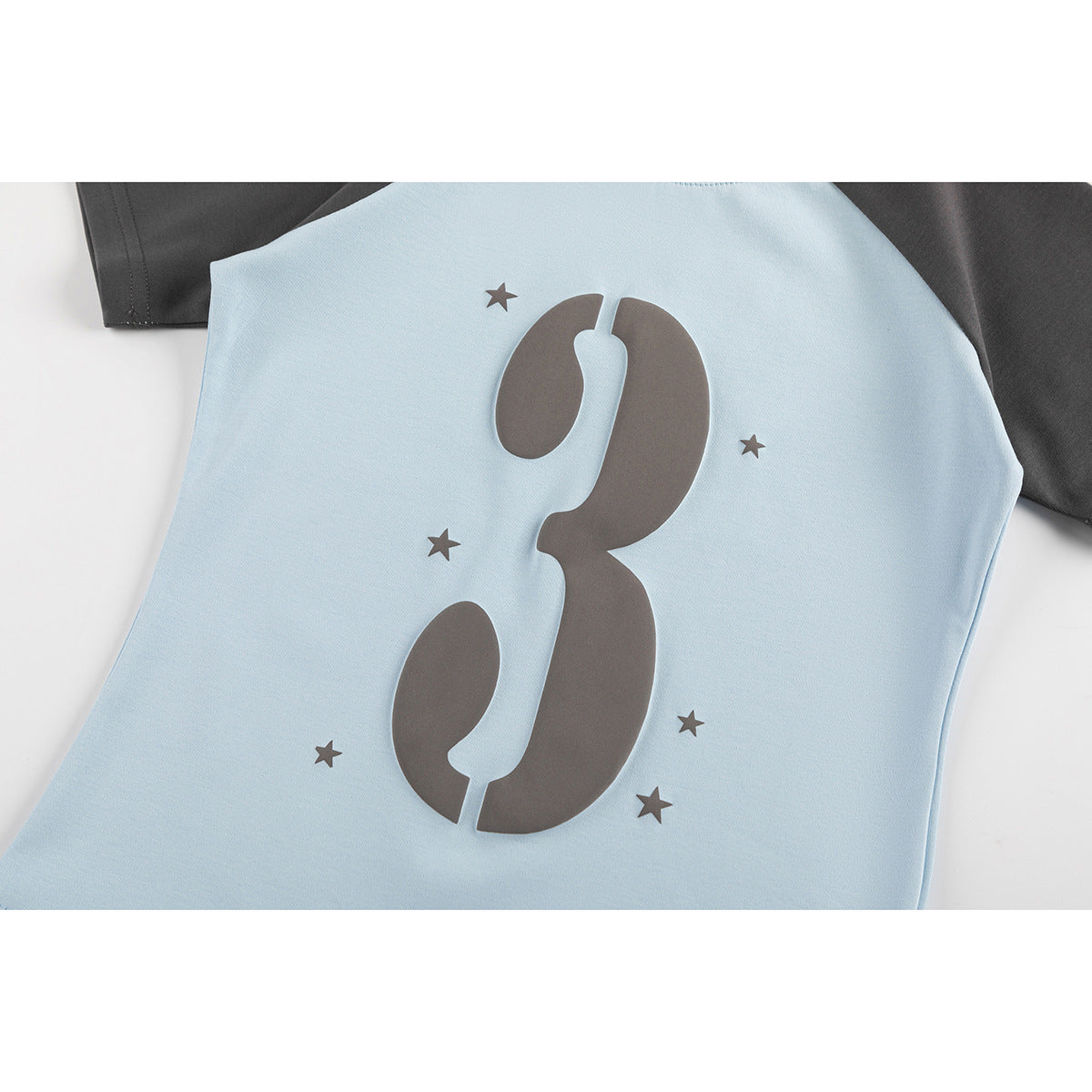 Close-up of a light blue T-shirt with a large dark gray number 3 and star print.