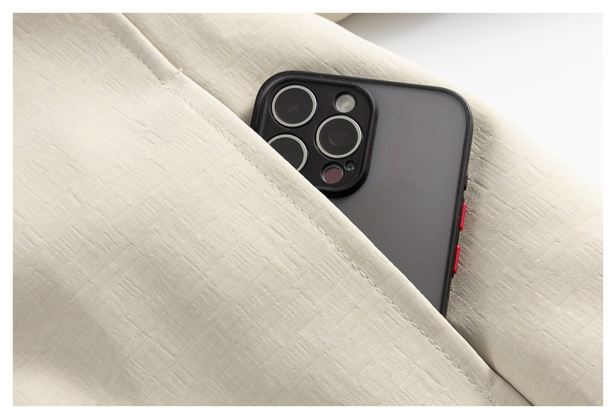 Close-up of a deep pocket in an ivory jacket, with a smartphone partly tucked inside.