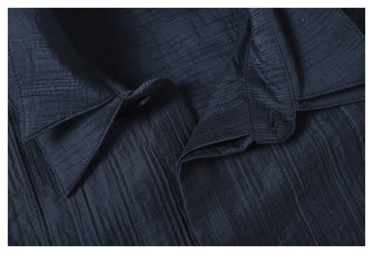 Close-up of the pointed collar and upper button area of a dark navy textured shirt.