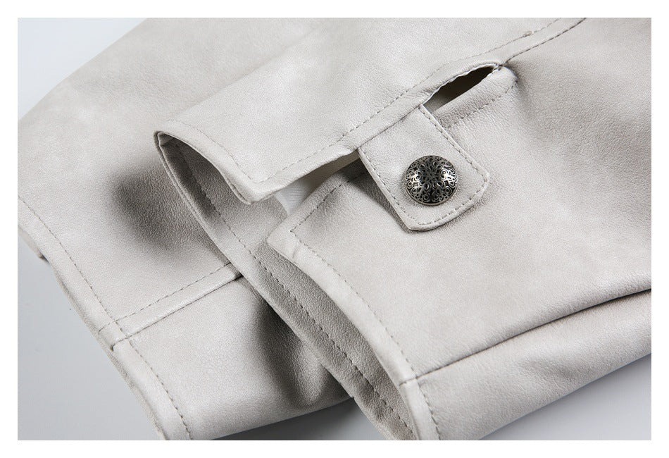 Close-up of a pale gray-beige garment cuff with a tab and ornate round snap.