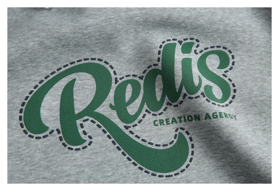 Close-up of the hoodie’s green script chest graphic with a dark dashed outline and small lettering.