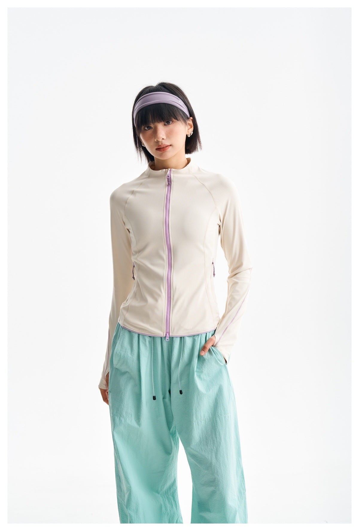Model wearing an ivory fitted zip-front jacket with lavender trim and loose mint-green trousers.