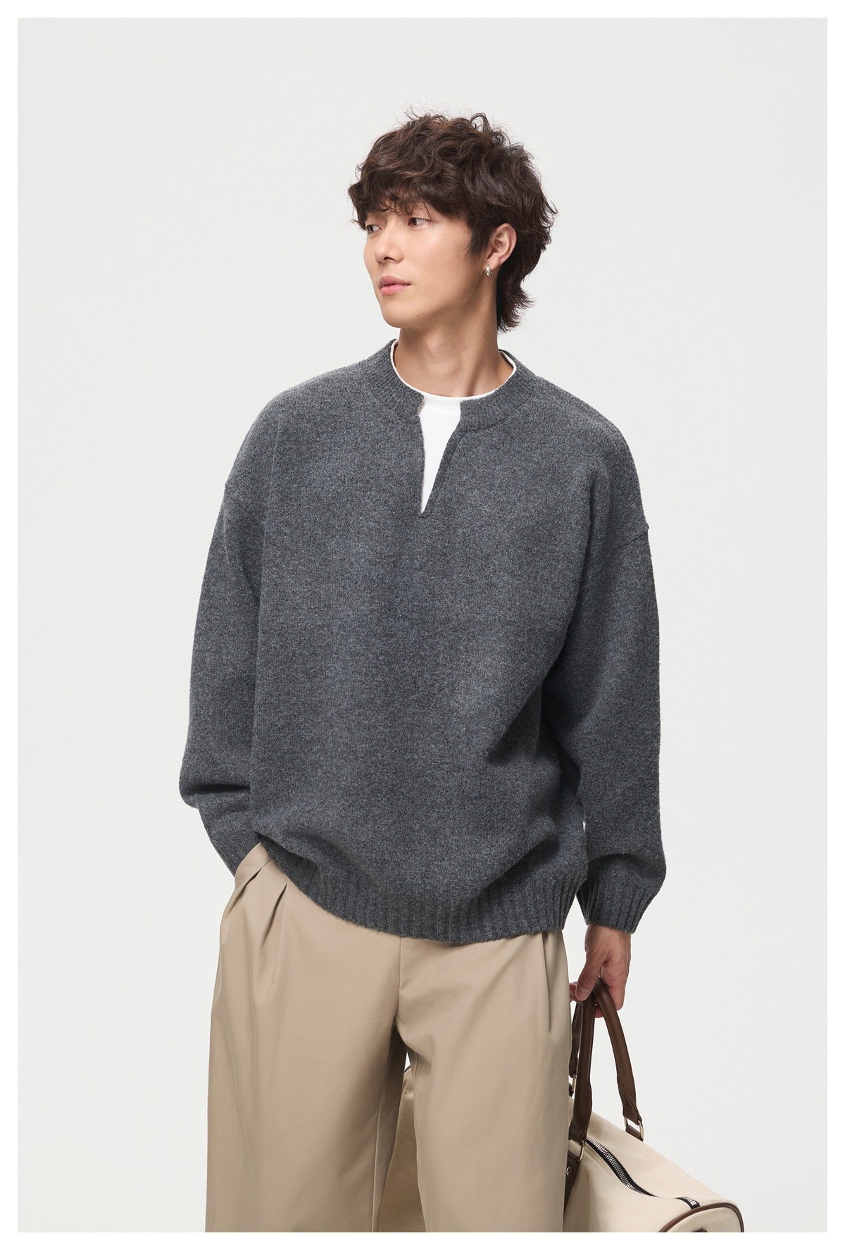 Model in a charcoal gray split-neck sweater, shown from the front with the neckline and ribbed cuffs visible.