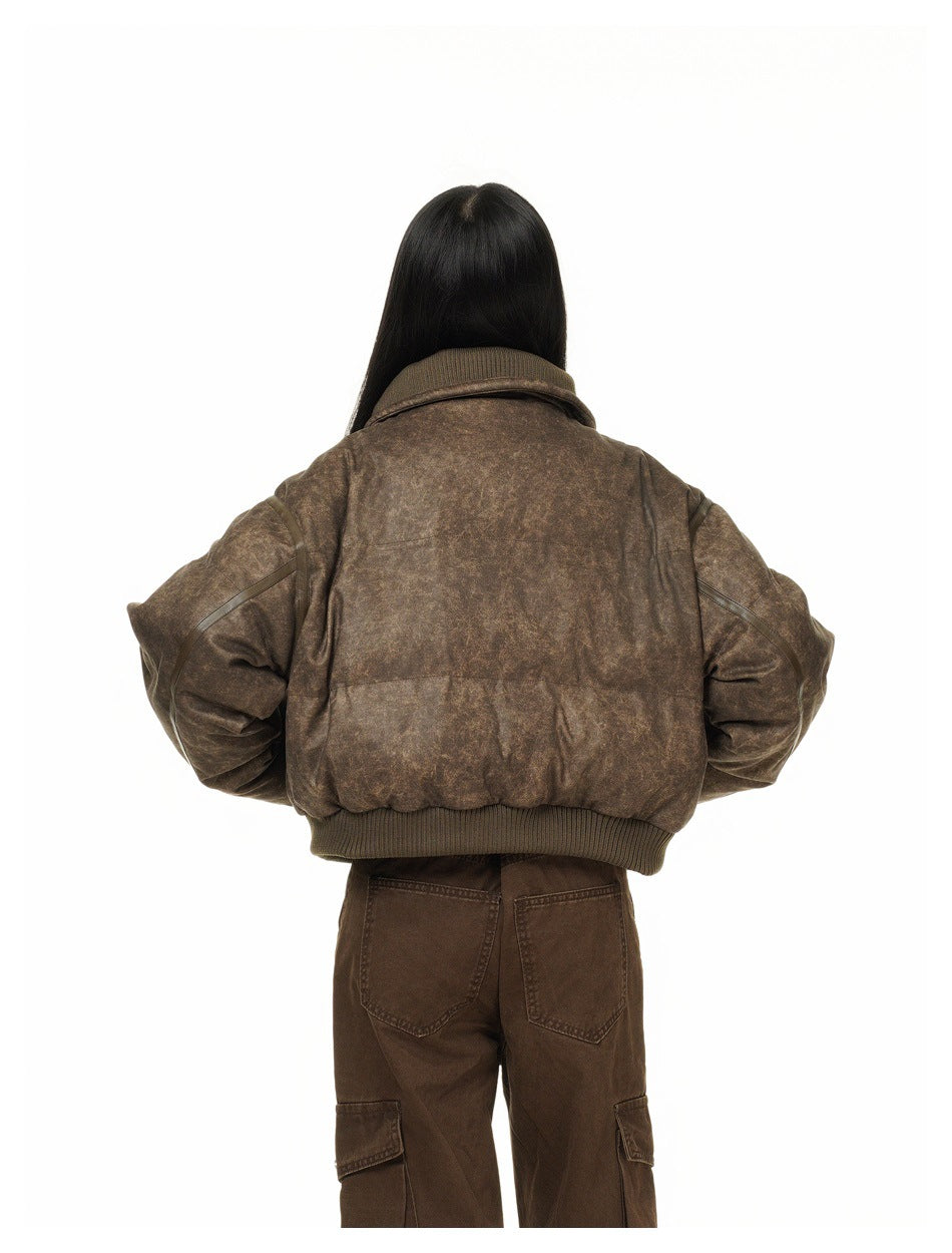 Back view of a model wearing a cropped mottled brown puffer jacket with a ribbed collar and hem.