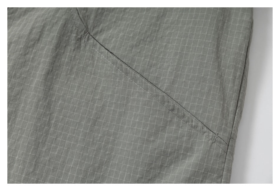 Close-up of a diagonal stitched seam on gray grid-patterned fabric.