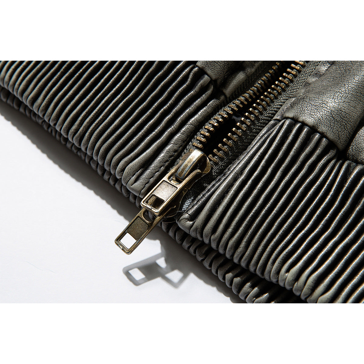 Close-up of the jacket's dark metal zipper and tightly ribbed waistband.