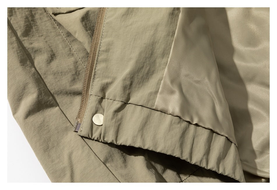 Close-up showing the khaki jacket's zipper, snap, gathered hem, and smooth inner lining.