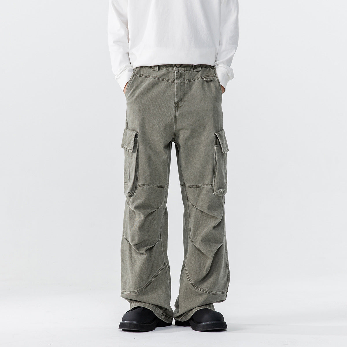 Model wearing gray-green wide-leg cargo pants with oversized flap pockets and articulated knee panels, front view.