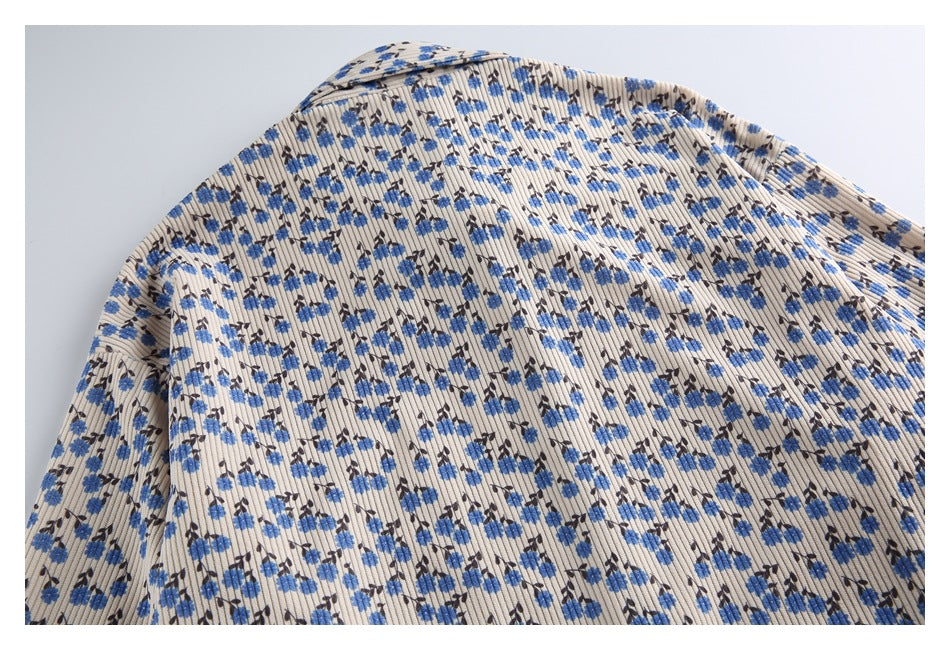 Close-up of a beige ribbed garment with small blue and dark floral print, showing the collar and shoulder.
