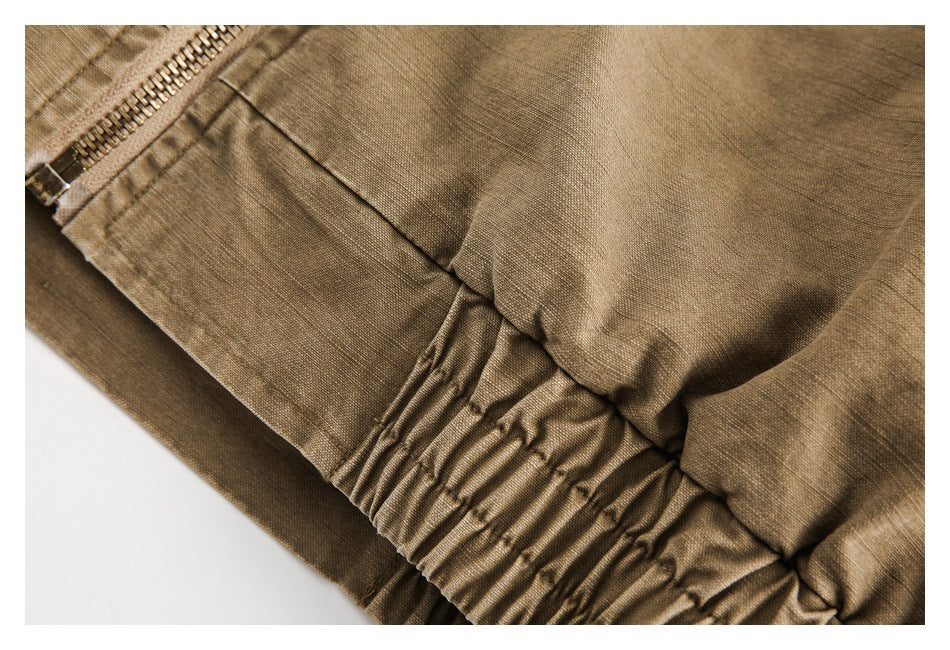Close-up of a tan garment showing a metal zipper, seam, and gathered elastic waistband.