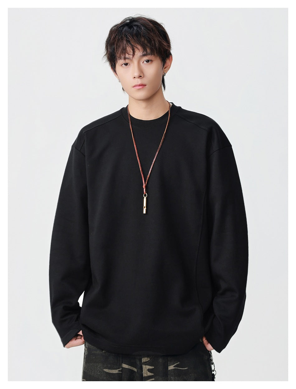 Front view of a model wearing a plain, oversized black crewneck top with long sleeves.