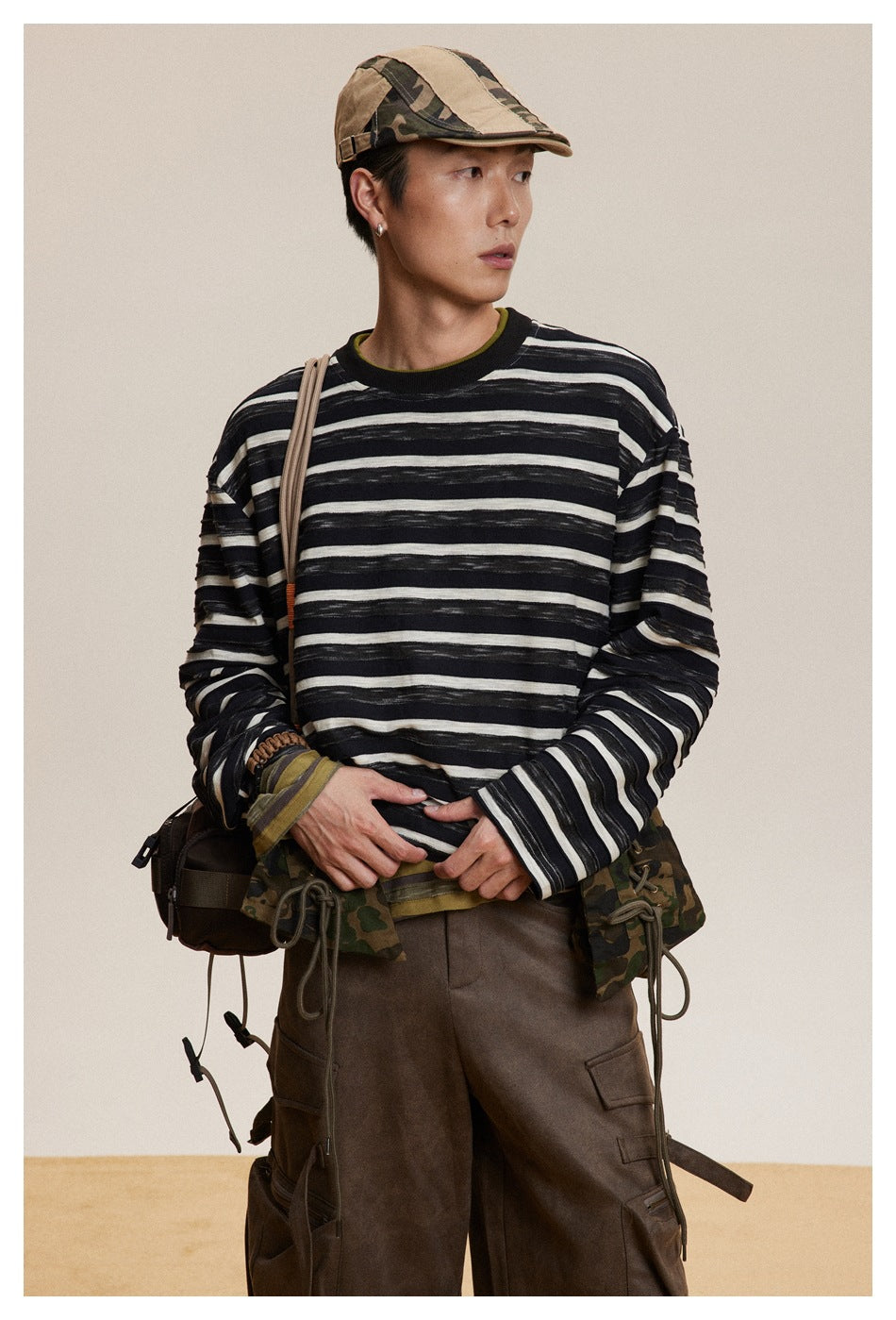 Close view of a model wearing a black-and-cream striped long-sleeve shirt with a ribbed dark collar.