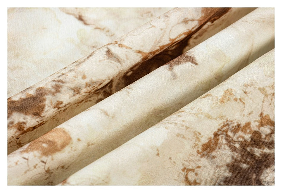 Close-up of folded cream fabric with an irregular brown abstract print.
