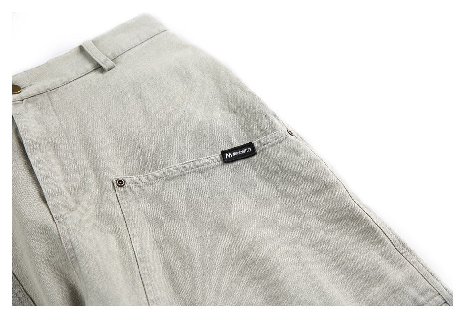 Close-up of a light gray-beige pocket with a small black sewn label and brass-tone button details.