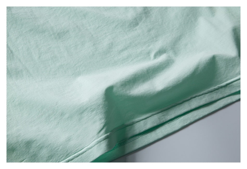 Close-up of a pale mint garment hem with visible stitching and textured fabric.