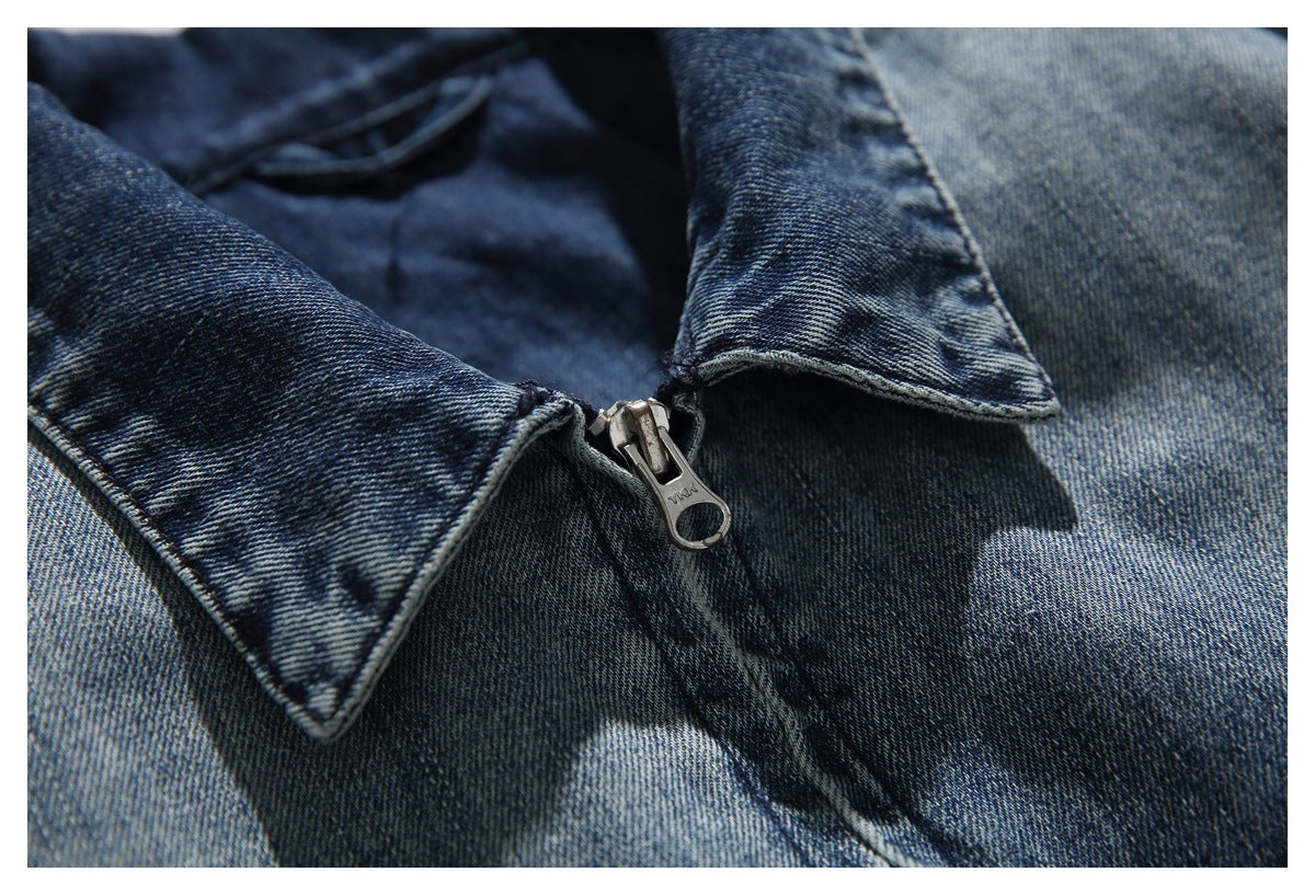Close-up of the pointed denim jacket collar and metal zipper against faded blue denim.