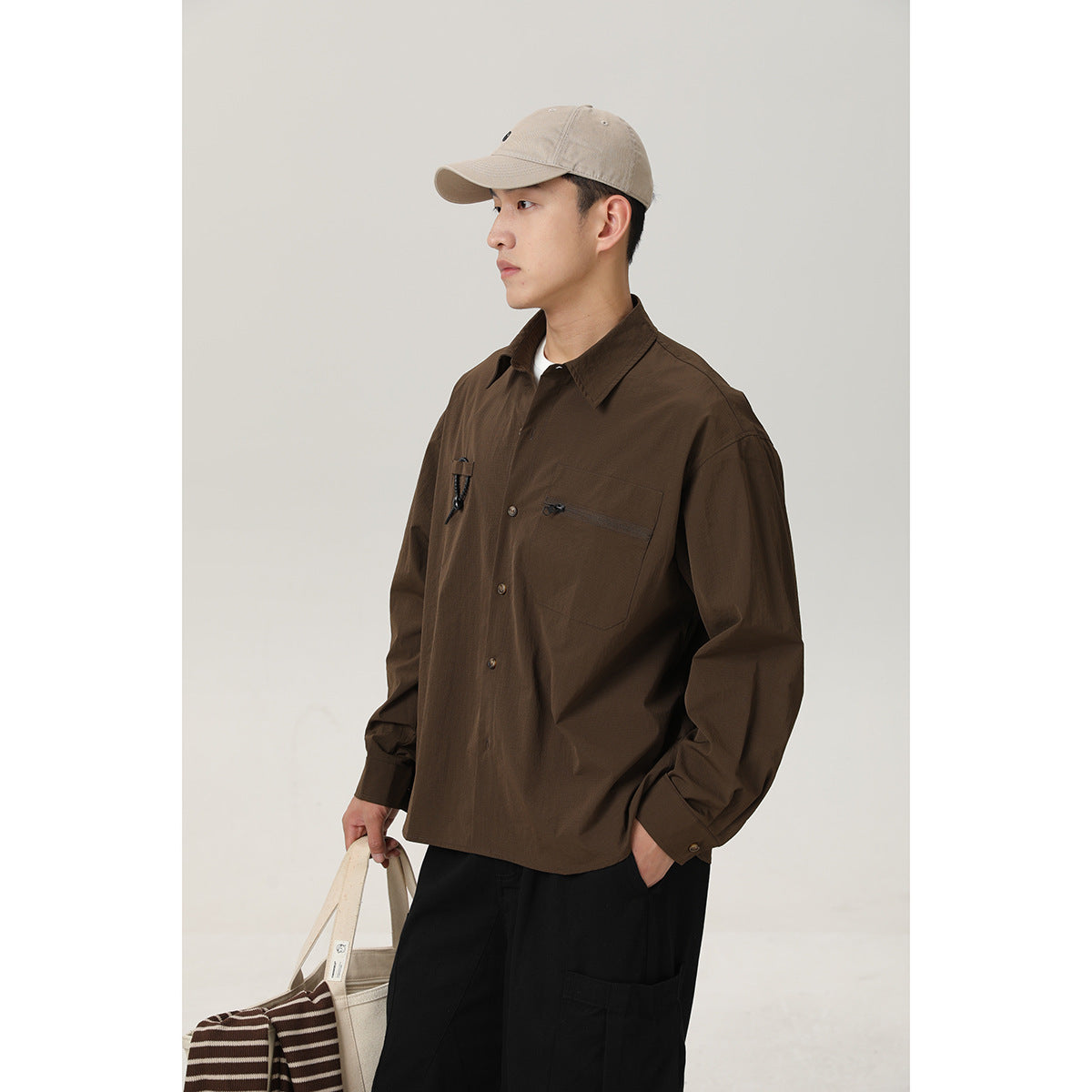 Three-quarter view of a model in a dark brown button-front shirt with a zip chest pocket and cord detail.