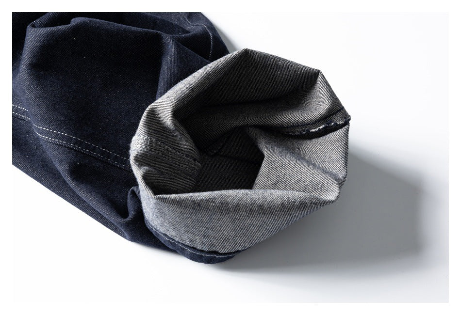 Close-up of a dark denim leg cuff turned inside out, revealing its gray reverse side.